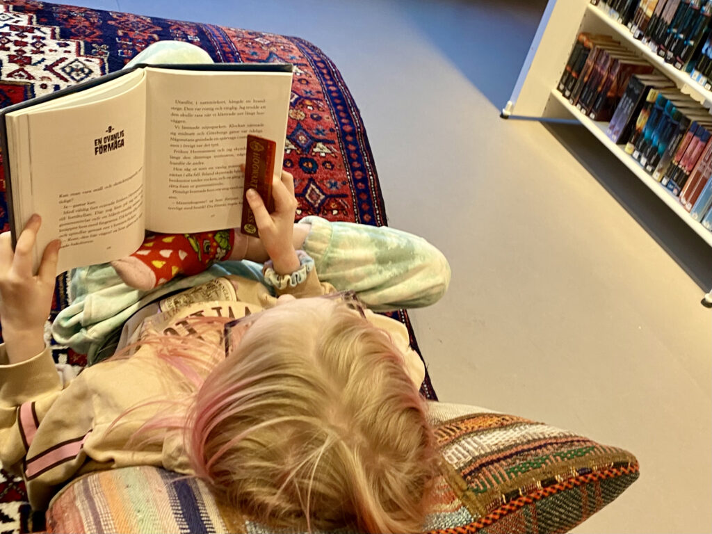 Barn som läser på bibliotek liggande på en "flygande matta"